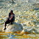 A local guide sits on yellow sulphur and mineral salt formations created by the upwelling springs of Dallol volcano.